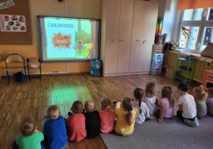 Dzieci oglądają film edukacyjny o jesieni z wykorzystaniem tablicy multimedialnej.