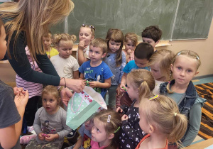 Pani nauczycielka częstuje dzieci owocowymi cukierkami.