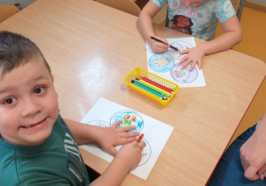 Dzieci kolorują kolorowankę według własnego pomysłu.