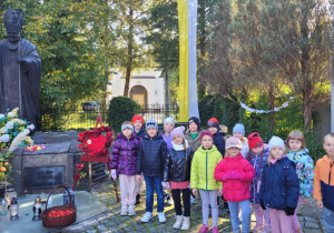 Dzieci z grupy Smerfy pozują przy pomniku Jana Pawła II.