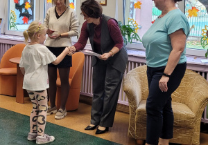 Dziewczynka odbiera gratulacje i dyplom od Pani Dyrektor.