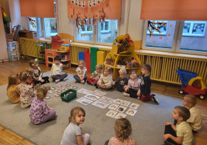 Dzieci siedzą na dywanie, słuchają ciekawostek na temat jeży.