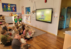 Zdjęcie dzieci oglądających film edukacyjny o historii pluszowego misia