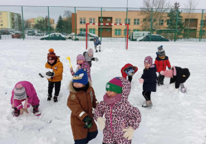 Dzieci lepią duże śniegowe kule.