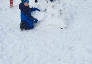 Dzieci budują igloo z śniegowych kul.