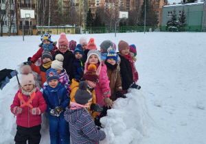 Dzieci pozują do zdjęcia w ulepionym przez siebie igloo.