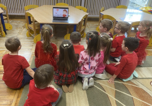 Dzieci siedzą na dywanie i oglądają film edukacyjny, pt. „Walentynki”.