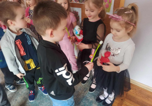 Chłopcy wręczają prezenty dziewczynkom z okazji Dnia Kobiet.