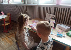 Chłopiec z grupy „Słoneczka” wykonuje makijaż swojej koleżance w „Salonie Piękności” przygotowanym z okazji Dnia Kobiet.