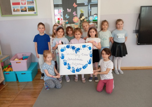 Dzieci z grupy Odkrywcy pozują z plakatem z okazji Dnia Autyzmu