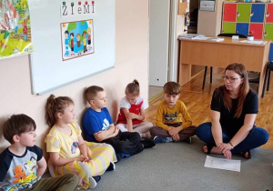 Nauczycielka i dzieci siedzą w kole i rozmawiają o rzeczach szkodliwych dla Ziemi.