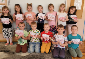 Dzieci z grupy Smerfy prezentują wykonane przez siebie biało-czerwone mapy Polski.