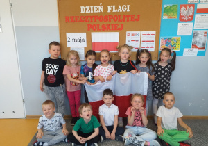 Dzieci z grupy Liski pozują do zdjęcia z dekoracją z obchodów Dnia Flagi.