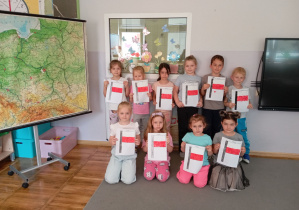 Dzieci z grupy Odkrywcy pozują z flagą Polski.