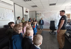 Przedszkolaki oglądają sprzęt w pokoju przyjmowania zgłoszeń pożarowych.