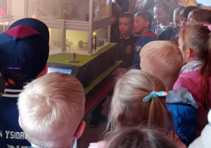 Dzieci w pokoju edukacyjnym oglądają makietę symulująca pożar.