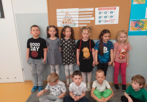 Dzieci z grupy Liski pozują do zdjęcia z piramidą żywienia i instrukcją mycia rąk.