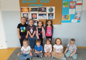 Dzieci pozują do zdjęcia przed ilustracjami związanymi ze Światowym Dniem Kosmosu.