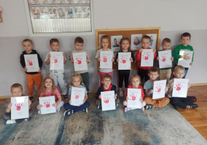 Dzieci z grupy „Słoneczka” pozują do zdjęcia z prezentem wykonanym z okazji Dnia Mamy i Taty.