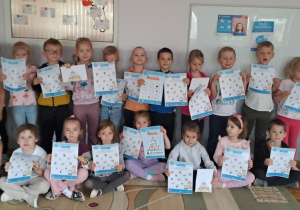 Misie pozują do zdjęcia grupowego z kartami pracy.