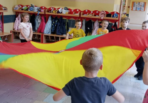 Przedszkolaki turlają piłeczkę po chuście animacyjnej.
