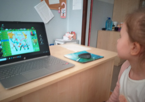 Zdjęcie przedstawia funkcje i możliwości programu Mały malarz z siedzącym obok dzieckiem.