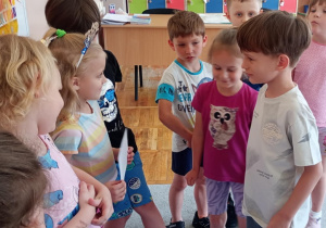Dziewczynka i chłopiec wręczają drugiej z jubilatek pamiątkowy dyplom.