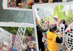 Przedszkolaki wypełniają motyla kolorowymi piłeczkami.