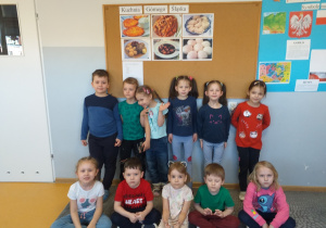 Zdjęcie przedstawia dzieci pozujące do zdjęcia na tle potraw regionalnych Górnego Śląska.