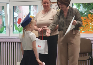 Dziewczynka z grupy Odkrywcy podczas wręczenia dyplomu oraz upominków za zdobycie nagrody Gold Award, przez Panią dyrektor oraz Panią wicedyrektor ZSP nr 9 w Bełchatowie.