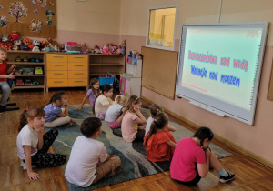 Dzieci z grupy Smerfy oglądają film edukacyjny dotyczący bezpiecznych wakacji nad morzem.