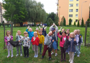 Dzieci przygotowane do akcji „Sprzątanie Świata” na trawniku w pobliżu przedszkola.
