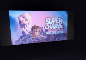 Dzieci siedzą w kinie, czekają na bajkę Super Charlie.