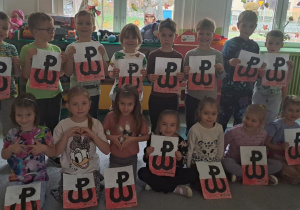 Dzieci z grupy „Motylki” pozują do zdjęcia z symbolami Polski walczącej.