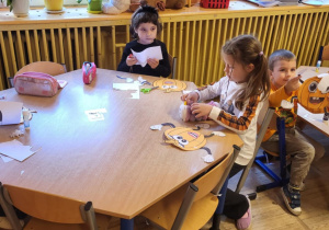 Dzieci siedzą przy stolikach, wykonują pracę plastyczną ,,Moja wyjątkowa dynia”.