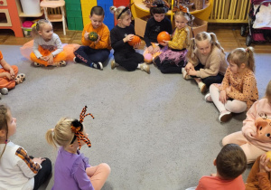 Dzieci siedzą w kole, oglądają różne rodzaje dyni.