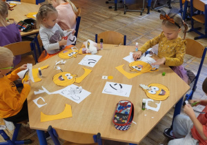 Dzieci siedzą przy stolikach, wykonują pracę plastyczną ,,Moja wyjątkowa dynia”.