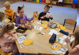 Dzieci siedzą przy stolikach, wykonują pracę plastyczną ,,Moja wyjątkowa dynia”.