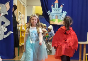 Dziewczynka przebrana za Elzę idzie po czerwonym dywanie w bajkowym pokazie mody.