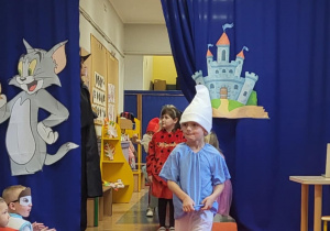 Chłopiec przebrany za Smerfa idzie po czerwonym dywanie w bajkowym pokazie mody.