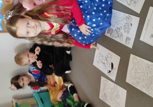 Dziewczynka wskazuje palcem ilustrację Pinokia, będącą odpowiedziom na zadaną zagadkę.