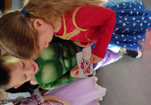 Dziewczynka i chłopiec staja obok siebie, każde z nich trzyma połowę ilustracji przedstawiającej Marshalla.