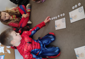 Chłopiec układa liczmany- płatki śniegu obok ilustracji z wizerunkiem Elzy.