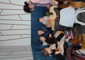 Dzieci siedzące przy stoliku w cukierni częstują się zakupionymi ciasteczkami.