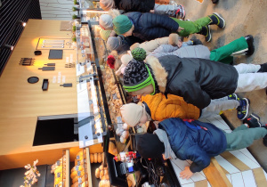 Przedszkolaki stoją przy ladzie sklepowej w piekarni- cukierni