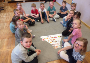 Zdjęcie przedstawia dzieci tworzące wspólnie własną piramidę zdrowego żywienia.