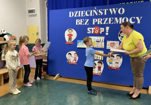 Chłopiec odbiera nagrodę od wicedyrektora za udział w konkursu Dzieciństwo Bez Przemocy.
