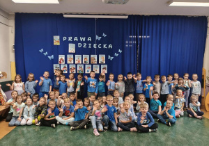 Przedszkolaki z grup najstarszych pozują do zdjęcia na tle dekoracji z informacjami o prawach dziecka.