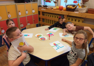 Zdjęcie przedstawia dzieci tworzące robota własnego pomysłu z gotowych figur geometrycznych.