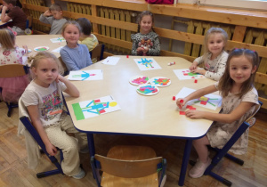 Zdjęcie przedstawia dzieci tworzące robota własnego pomysłu z gotowych figur geometrycznych.